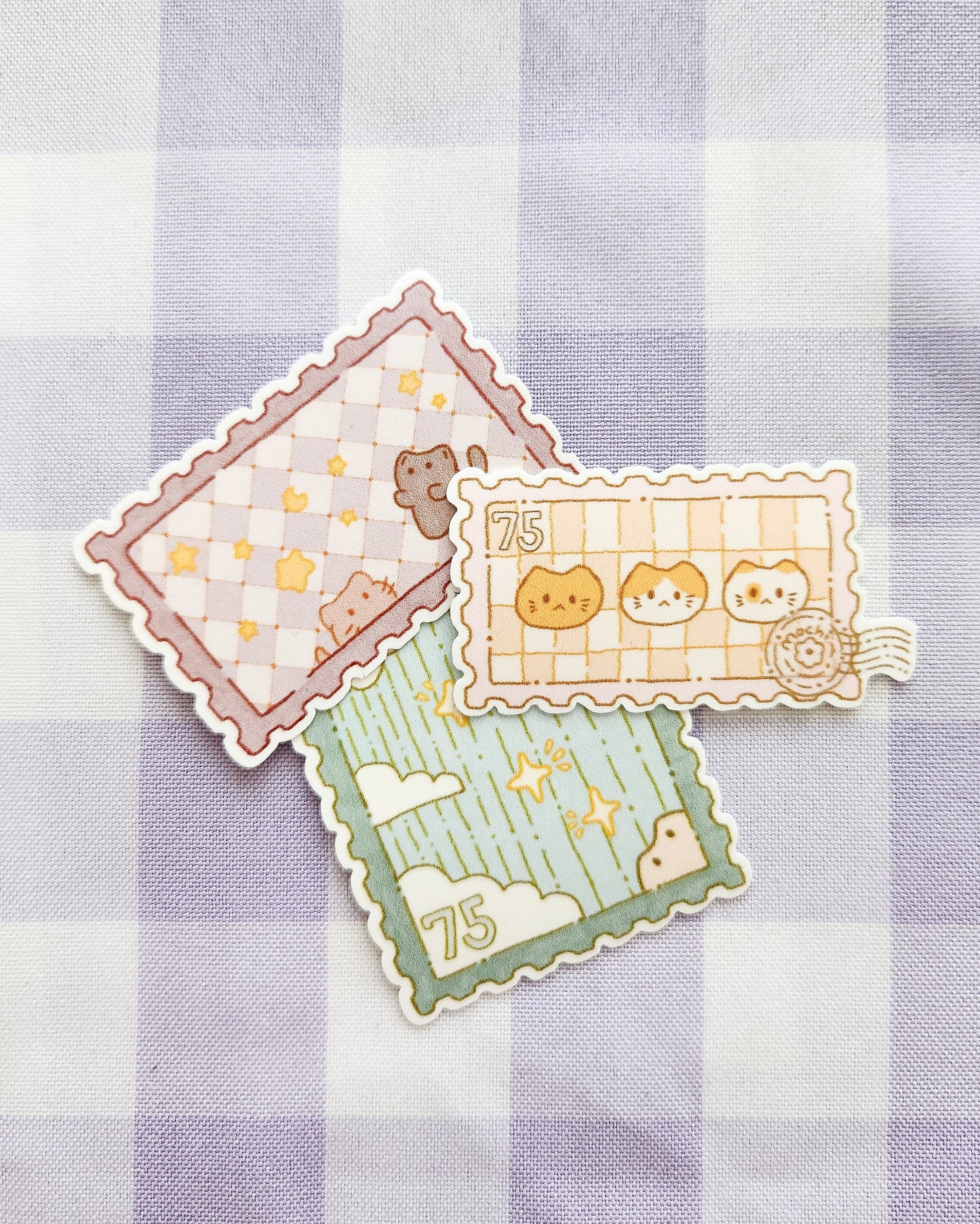 Three decorative stamps with cartoon designs on a checkered fabric background