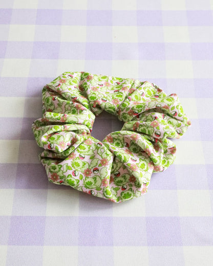 Green floral scrunchie on a purple and white checkered background