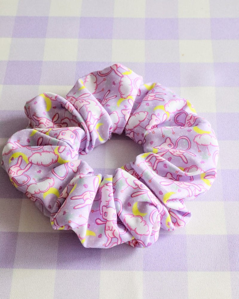 Pink scrunchie with yellow patterns on a purple and white checkered background