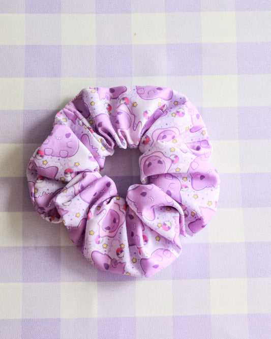 Purple hair scrunchie with pink pig pattern on a purple and white checkered background