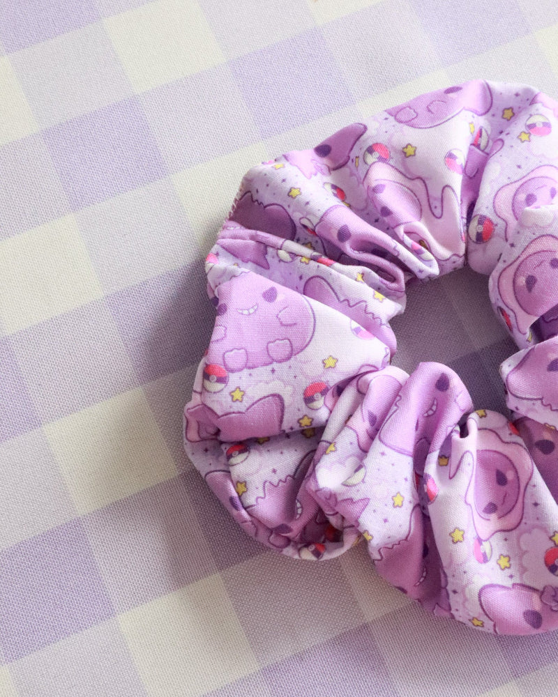 Pink scrunchie with cartoon character design on a checkered background