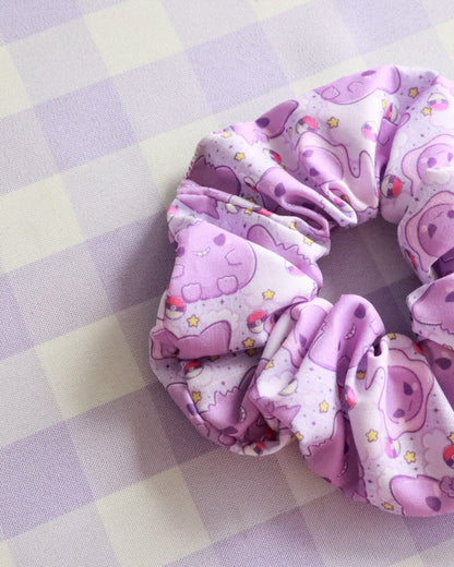 Pink scrunchie with cartoon character design on a checkered background