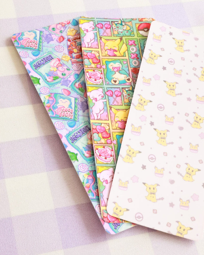 Three colorful stationery items with cartoon designs on a checkered background