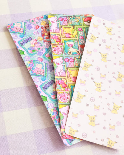 Three colorful notebooks with cartoon designs on a checkered background