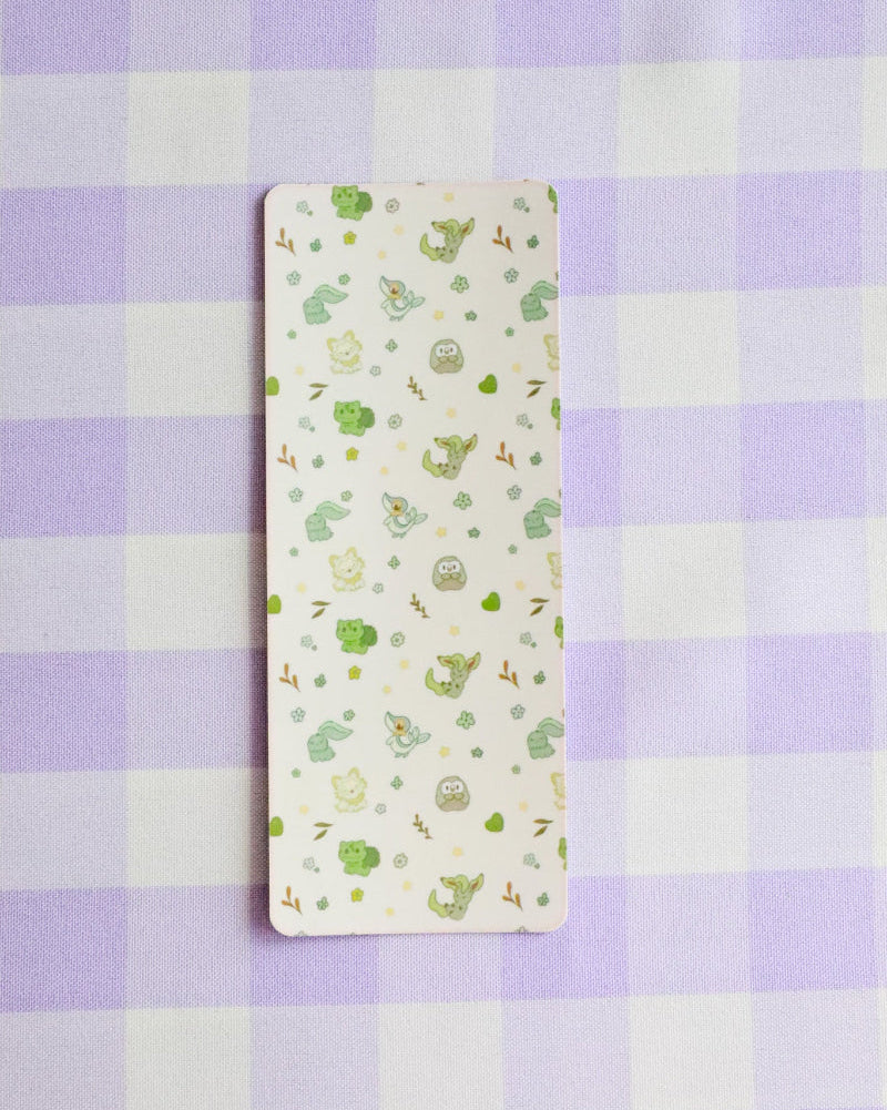Small rectangular fabric sample with green patterns on a purple and white checkered background