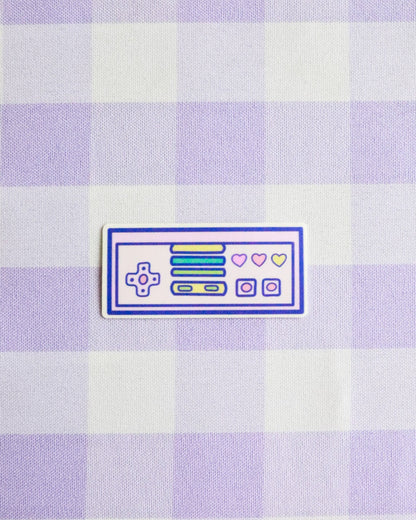 Checkered fabric with a retro gaming console patch on a light purple and white checkered background