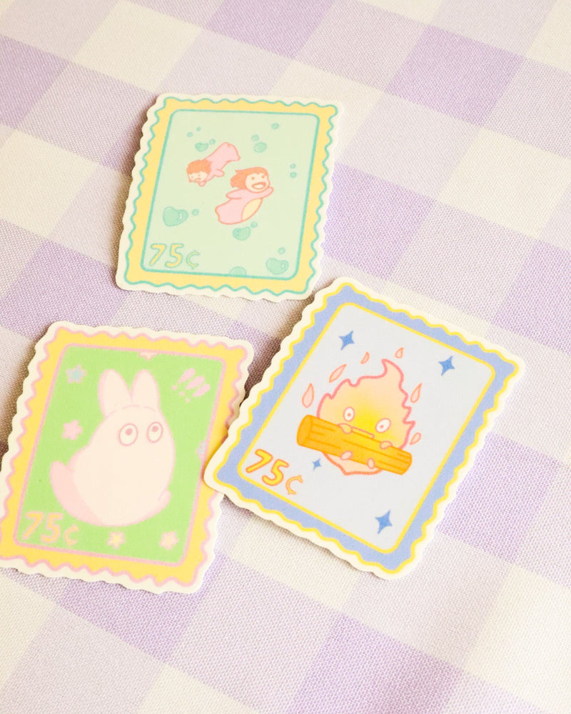 Three colorful postage stamps with cartoon designs on a checkered fabric background