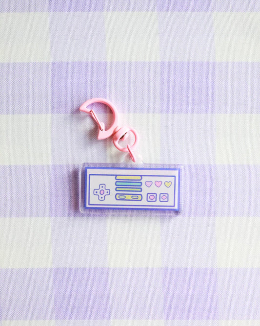 Keychain with a retro gaming console design on a purple and white checkered background