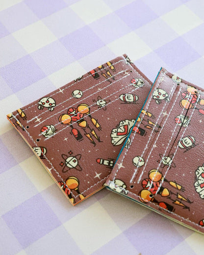 Two card holders with space-themed design on a checkered background