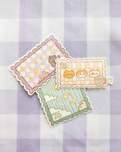 Three decorative stamps with cartoon designs on a checkered fabric background