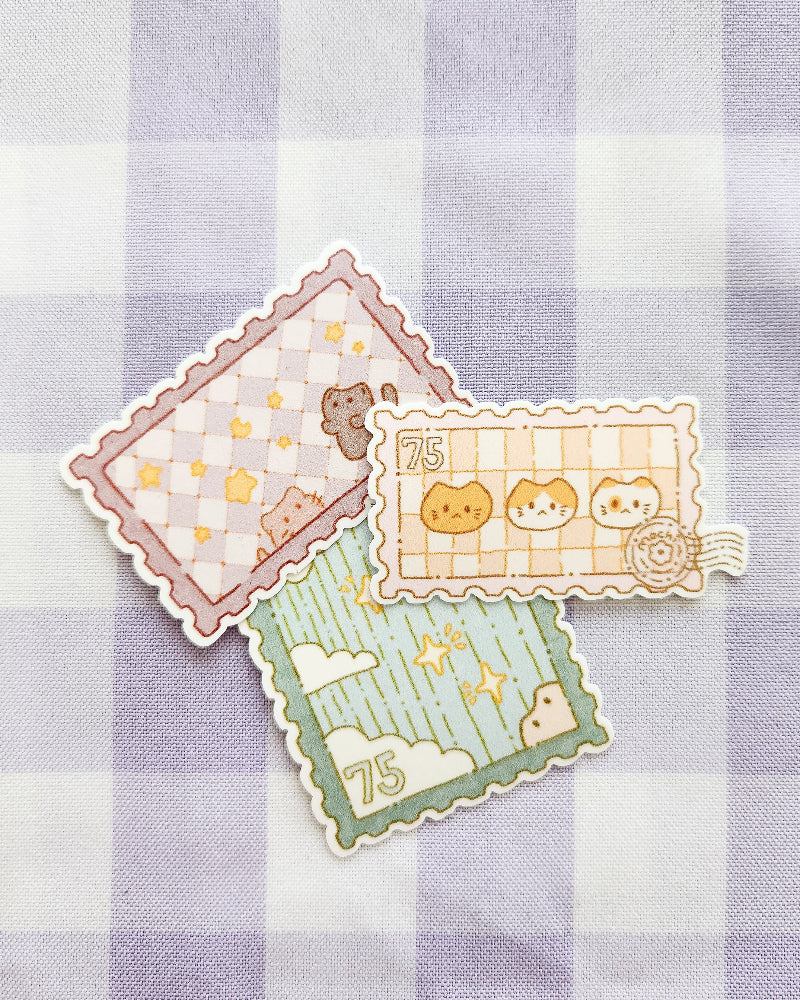 Three decorative stamps with cartoon designs on a checkered fabric background