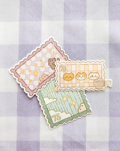 Three decorative stamps with cartoon designs on a checkered fabric background