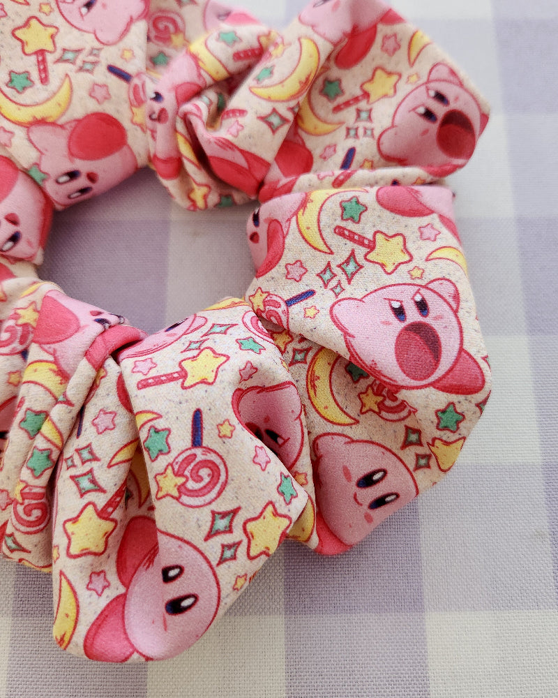 Two colorful scrunchies with cartoon character design on a striped fabric background