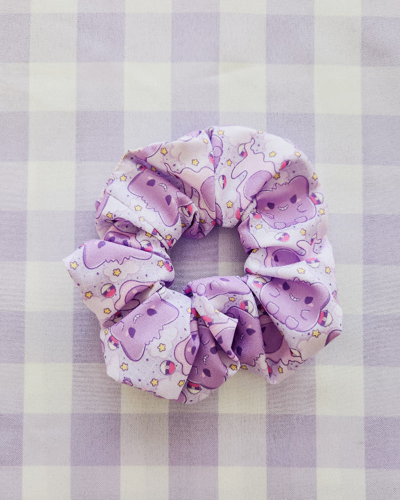 Purple scrunchie with cartoon designs on a purple and white checkered background