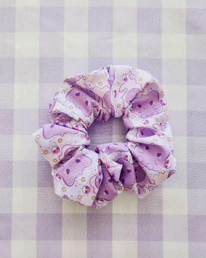 Purple scrunchie with cartoon designs on a purple and white checkered background